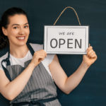 small business owner holding the sign for the reopening
